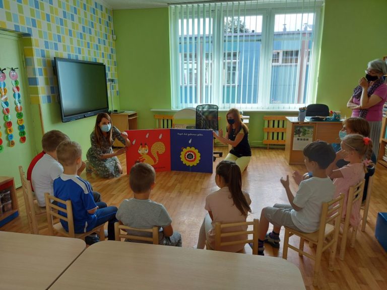 ratu sėdi būrelis vaikų ir dalyvauja biblioterapijos užsiėmime