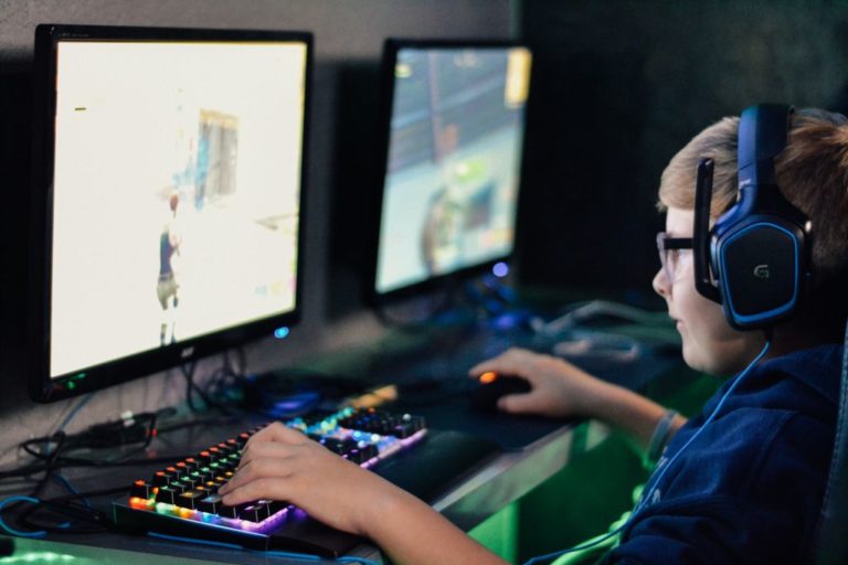 Vaikas užsiėmęs prie dviejų kompiuterio ekranų