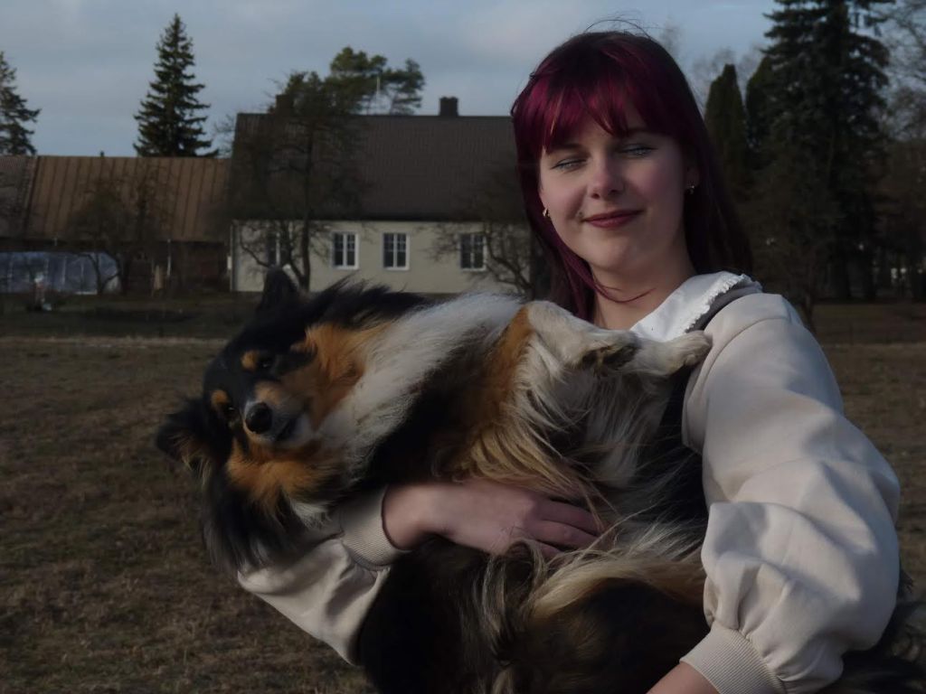 Mergina šypsosi ir laiko šunį ant rankų