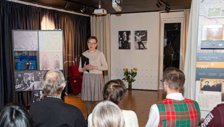 Moteris kalba priešais žmonių auditoriją namų aplinkoje