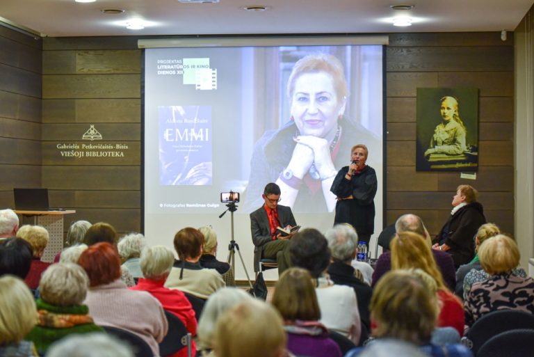 Moteris šneka į mikrofoną prieš dalyvių auditoriją