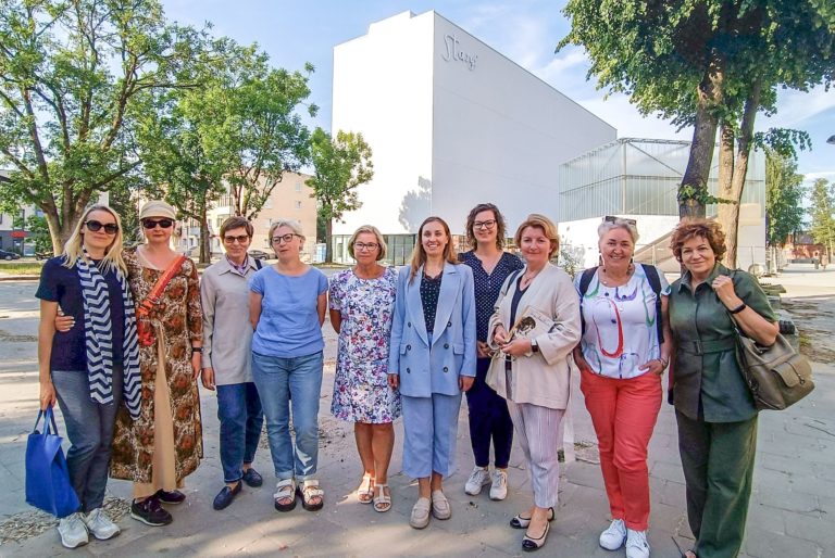 Grupė moterų šypsosi S. Eidrigevičiaus menų centro fone
