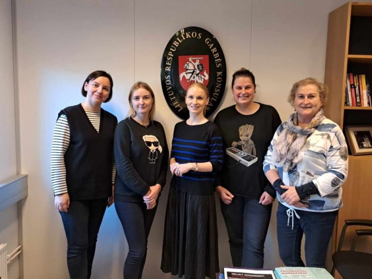 Penkios įvairaus amžiaus moterys užrašo Lietuvos Respublikos garbės konsulatas fone
