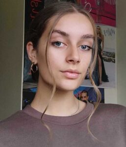 Mergina rimtai žvelgia kambario fone