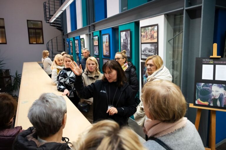 Būrelis žmonių klauso gidės pasakojimo bibliotekos Atrijaus terasos erdvėje