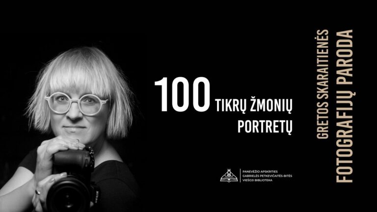 Moteris trumpais šviesiais plaukais ir su akiniais laiko fotoaparatą ir žiūri tiesiai juodame fone