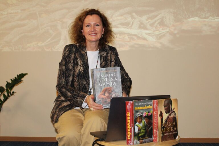 Kelionė į laukinės gamtos pasaulį su Egle Aukštakalnyte-Hansen Moteris sėdi ir šypsosi sienos fone šalia ant stalo sudėtų knygų