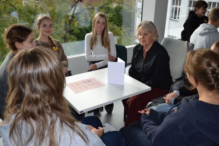 Vokiečių kalba be vadovėlio – tikra kalbų kavinės atmosfera Aplinkui stalą sėdi jaunimas ir vyresnio amžiau moteris