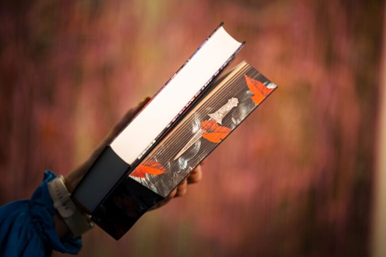 Ranka, laikanti dvi knygas išsiliejusiame vyšniniame fone