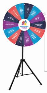 Spalvingas stovintis laimės ratas ant trikojo stovo, padalytas į kelis segmentus su skirtingomis užduotimis ir užrašais, centre – logotipas „Biblioteka visiems“