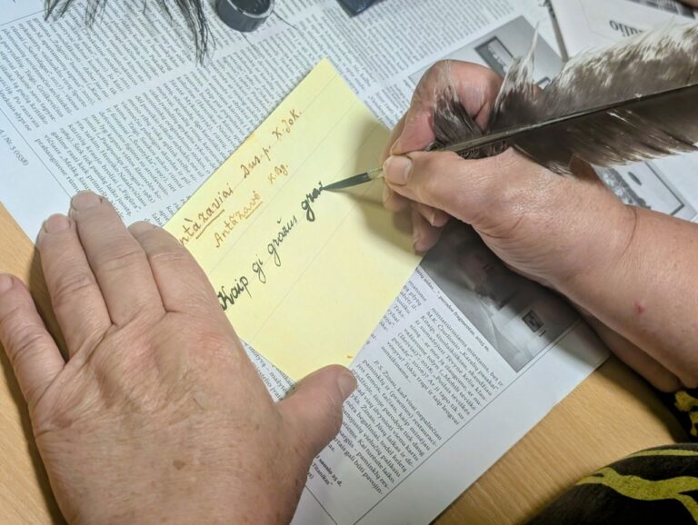 Moters rankos, vedžiojančios žodžius plunksna juodu rašalu