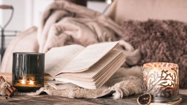 jauki namų aplinka su degančiomis žvakėmis, girlianda ir atversta knyga