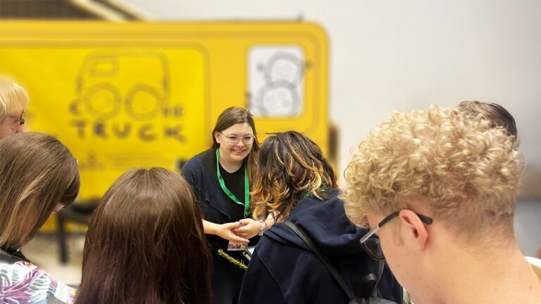 Besišypsanti moteris ir nusisukusių jaunų žmonių galvos geltono furgonėlio fone