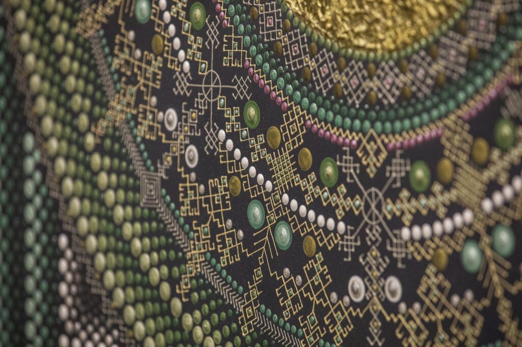 Paveikslėlyje matome detalų geometrinio rašto fragmentą, kuriame derinamos įvairios spalvos ir formos. Išryškėja žalios, baltos, geltonos ir rožinės spalvos taškai bei linijos, sudarančios sudėtingus ornamentus ir abstrakčius geometrinius motyvus. Raštas yra labai smulkus ir detalus, su subtiliais aukso atspalviais, kurie prideda švytėjimo ir gilumo. Šis kūrinys pasižymi tikslumu ir išsiskiria savo spalvų ir formų deriniu.