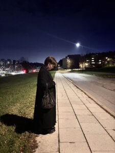 mergina Prietemėjančiame mieste stovi šonu ir žvelgia palenkusi galvą į šaligatvį