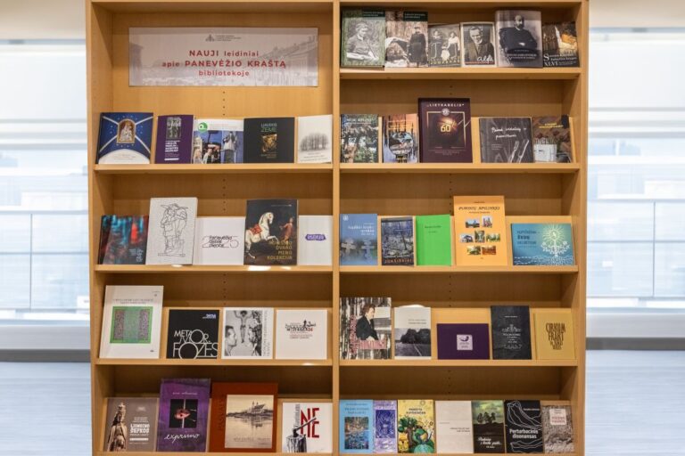 Knygų lentynose išdėliotos knygos, susijusios su Panevėžio kraštu